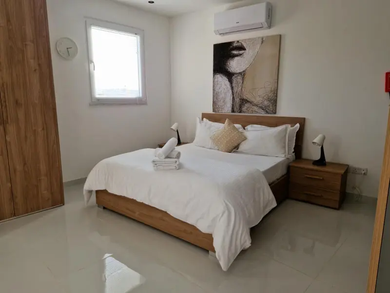 Une chambre lumineuse avec un grand lit et une décoration murale.