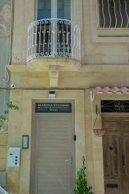 Façade d'un bâtiment avec un balcon en fer forgé et une entrée.