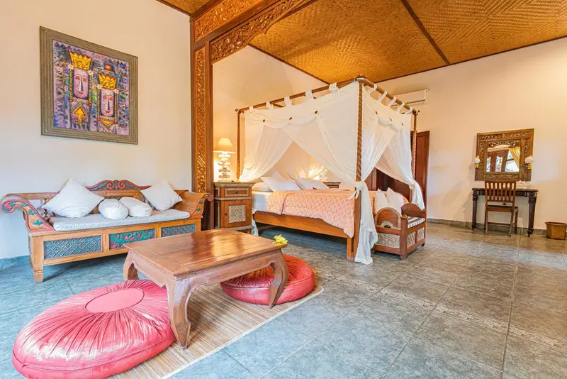 Une chambre lumineuse avec un grand lit à baldaquin et un coin salon.