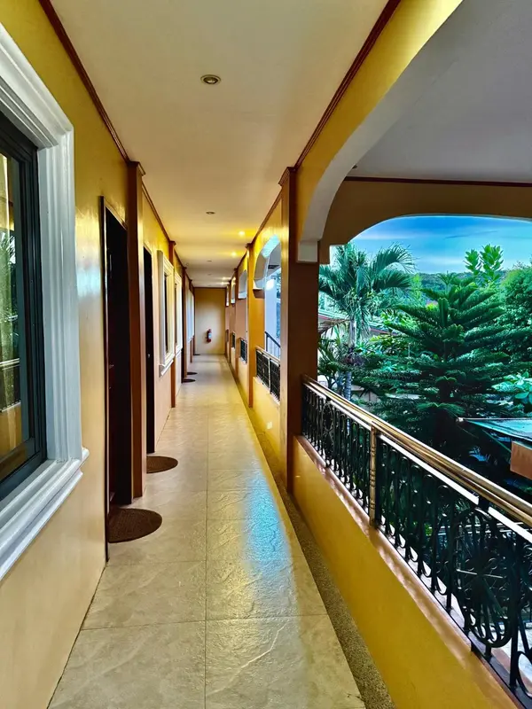 Couloir intérieur d'un bâtiment avec vue sur une végétation luxuriante.