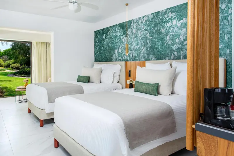 Deux lits simples avec oreillers verts dans une chambre lumineuse.