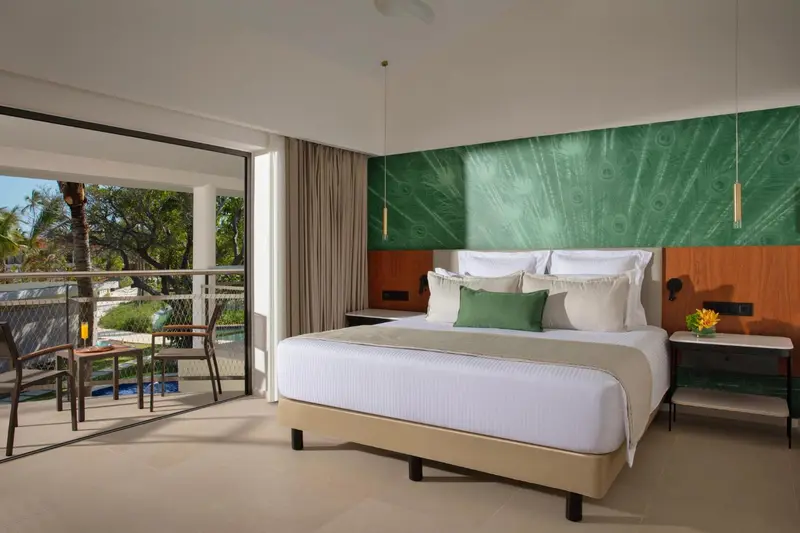 Une chambre lumineuse avec un grand lit et un accès à un balcon.