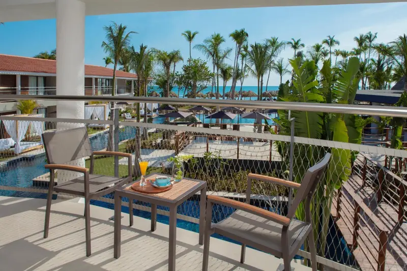Terrasse avec table basse et boissons, vue sur une piscine et la mer.