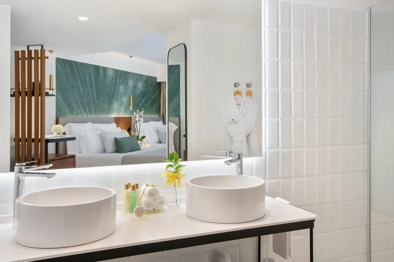 Double vasque blanche sur un comptoir clair dans une salle de bain lumineuse.