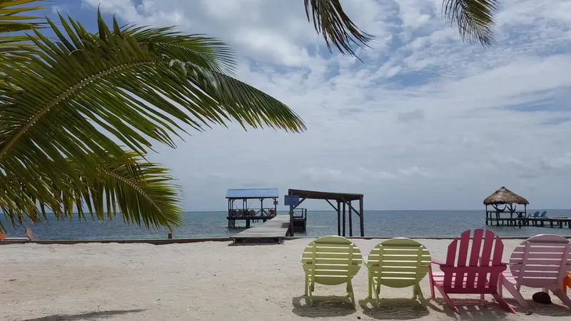 Plage de sable blanc avec chaises longues colorées et pontons en bois sur l'océan.