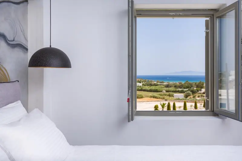 Une chambre lumineuse donne sur une vue dégagée sur la mer et la végétation.