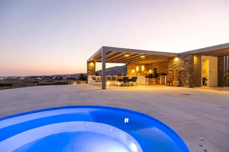 Terrasse lumineuse avec coin repas et jacuzzi au premier plan, vue sur le paysage au loin.