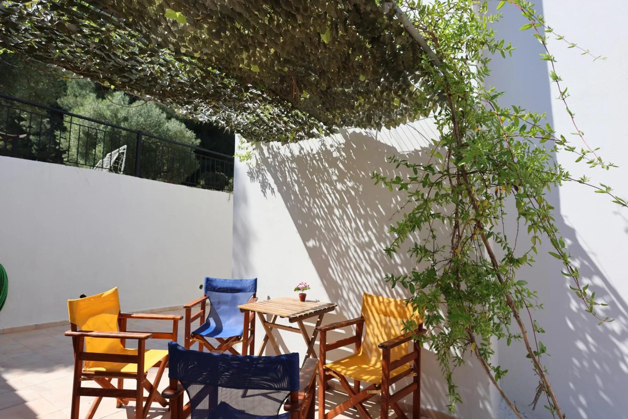 Terrasse ombragée avec mobilier de jardin et végétation.