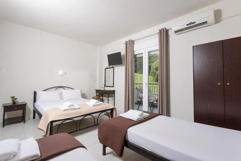 Une chambre lumineuse avec deux lits simples et un lit double.