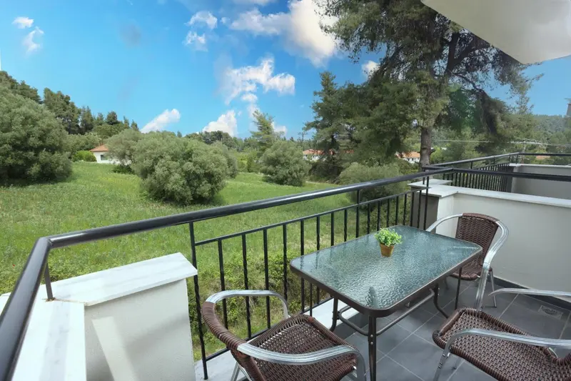 Une terrasse avec une table et des chaises offre une vue sur la végétation et un paysage verdoyant.