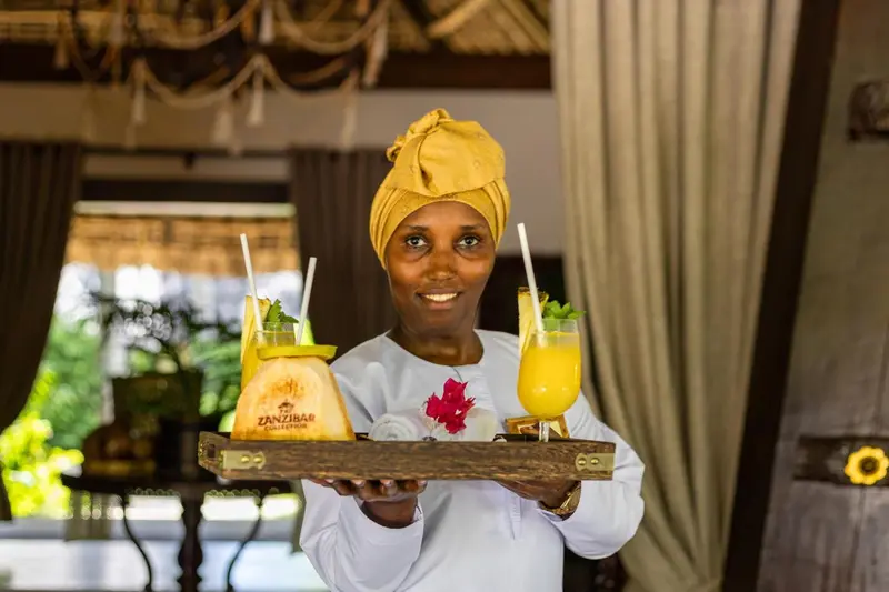 Une serveuse souriante présente un plateau de boissons colorées.