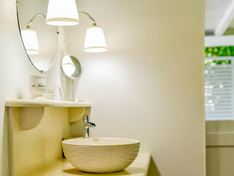Un lavabo blanc est éclairé par des lampes murales dans une salle de bain.