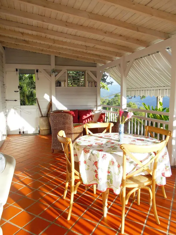 Une table ronde fleurie est mise en scène sur une terrasse carrelée.