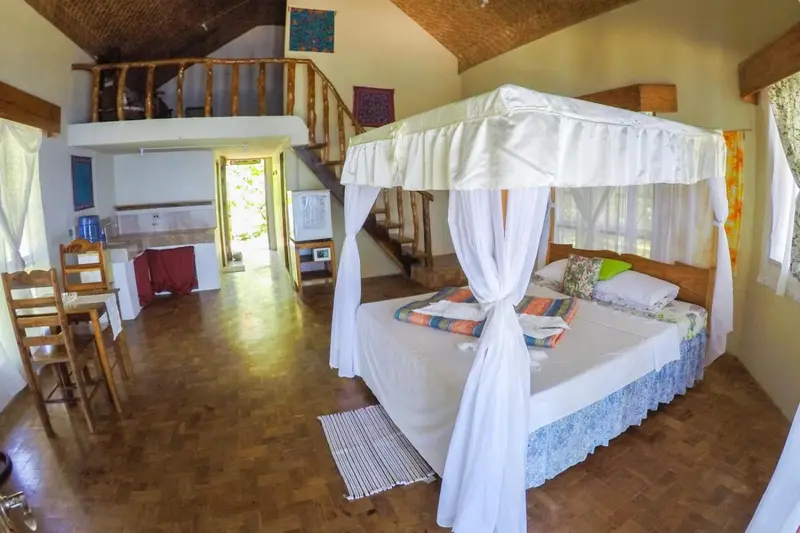 Une chambre lumineuse avec un lit à baldaquin et un coin repas.
