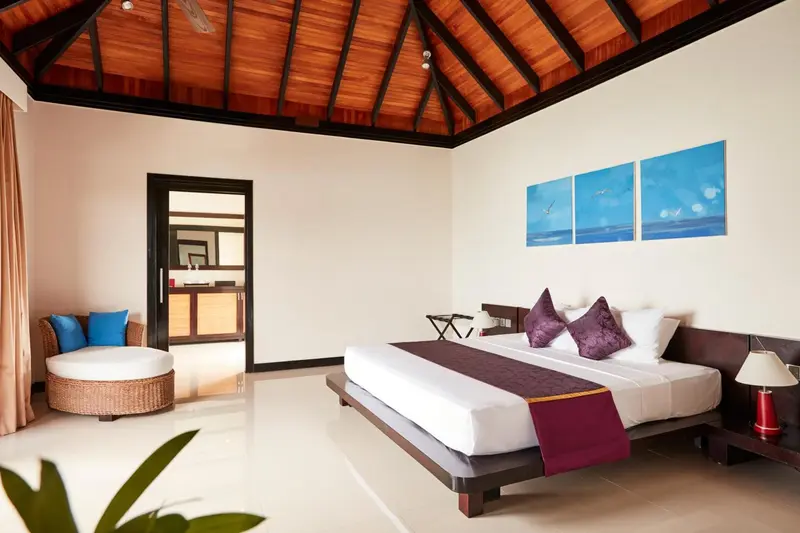 Une chambre lumineuse avec un lit king-size et un coin salon.