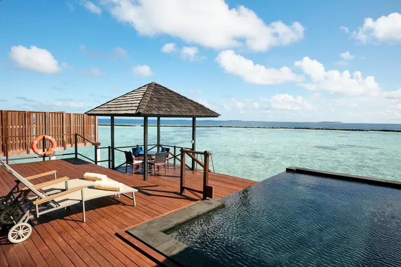 Terrasse en bois avec mobilier de détente et piscine à débordement face à la mer.
