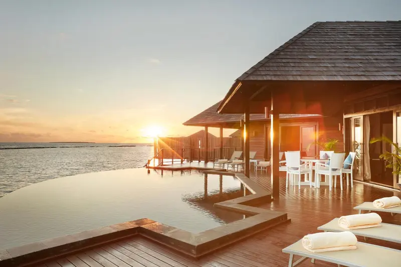 Terrasse avec piscine et vue sur la mer au coucher du soleil.