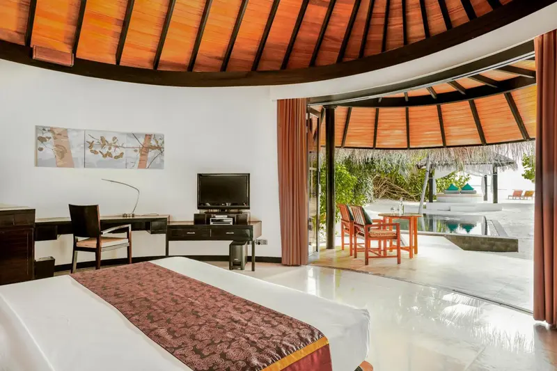 Une chambre lumineuse s'ouvre sur une terrasse avec vue sur une piscine.