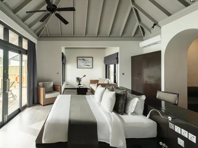Une chambre lumineuse avec un grand lit et un coin salon.