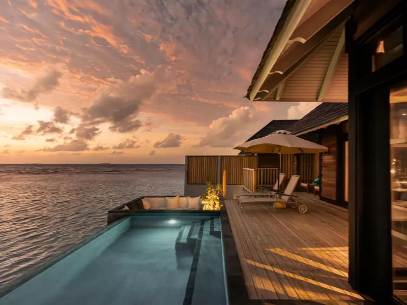 Terrasse avec piscine privative donnant sur l'océan au coucher du soleil.