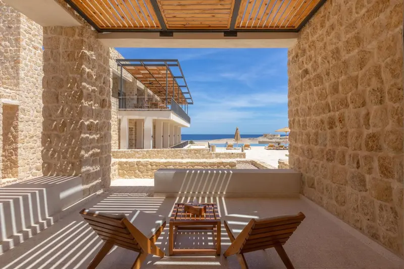 Terrasse avec mobilier en bois donnant sur une vue mer et piscine.
