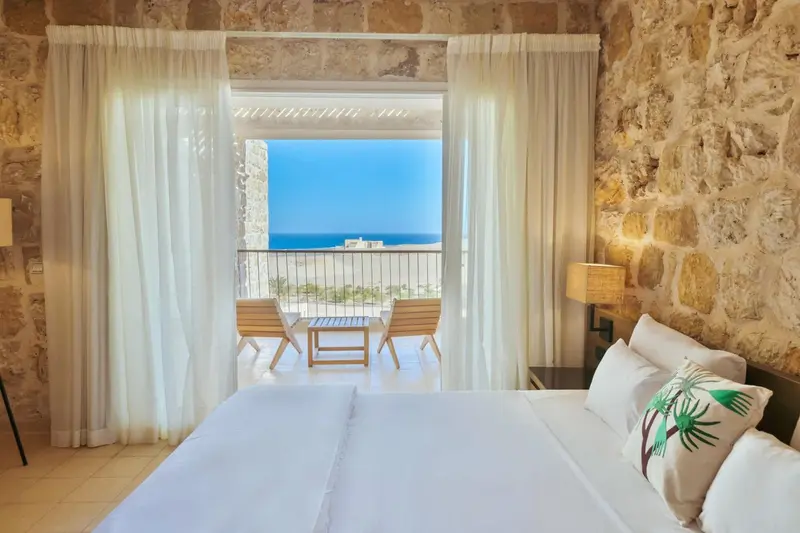 Une chambre lumineuse s'ouvre sur une vue mer et une terrasse aménagée.