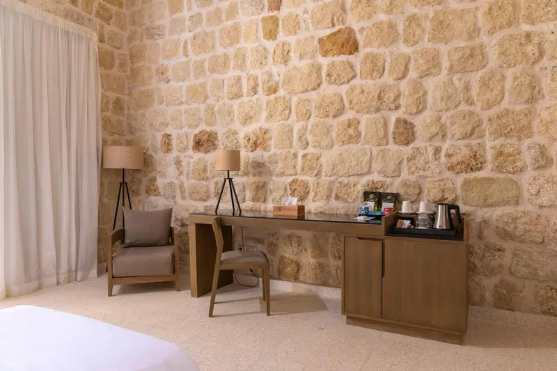 Espace de travail avec chaise et lampes dans une chambre au mur de pierre.