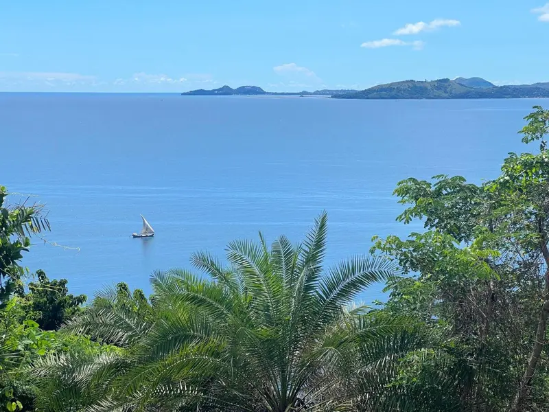 Vue panoramique sur une baie turquoise et une île verdoyante.
