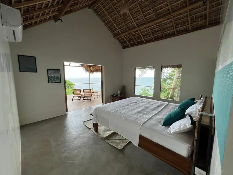 Une chambre lumineuse s'ouvre sur une terrasse avec vue sur la mer.