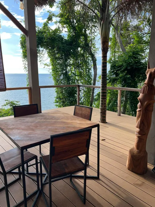 Une table et des chaises en bois sur une terrasse avec vue sur la mer.
