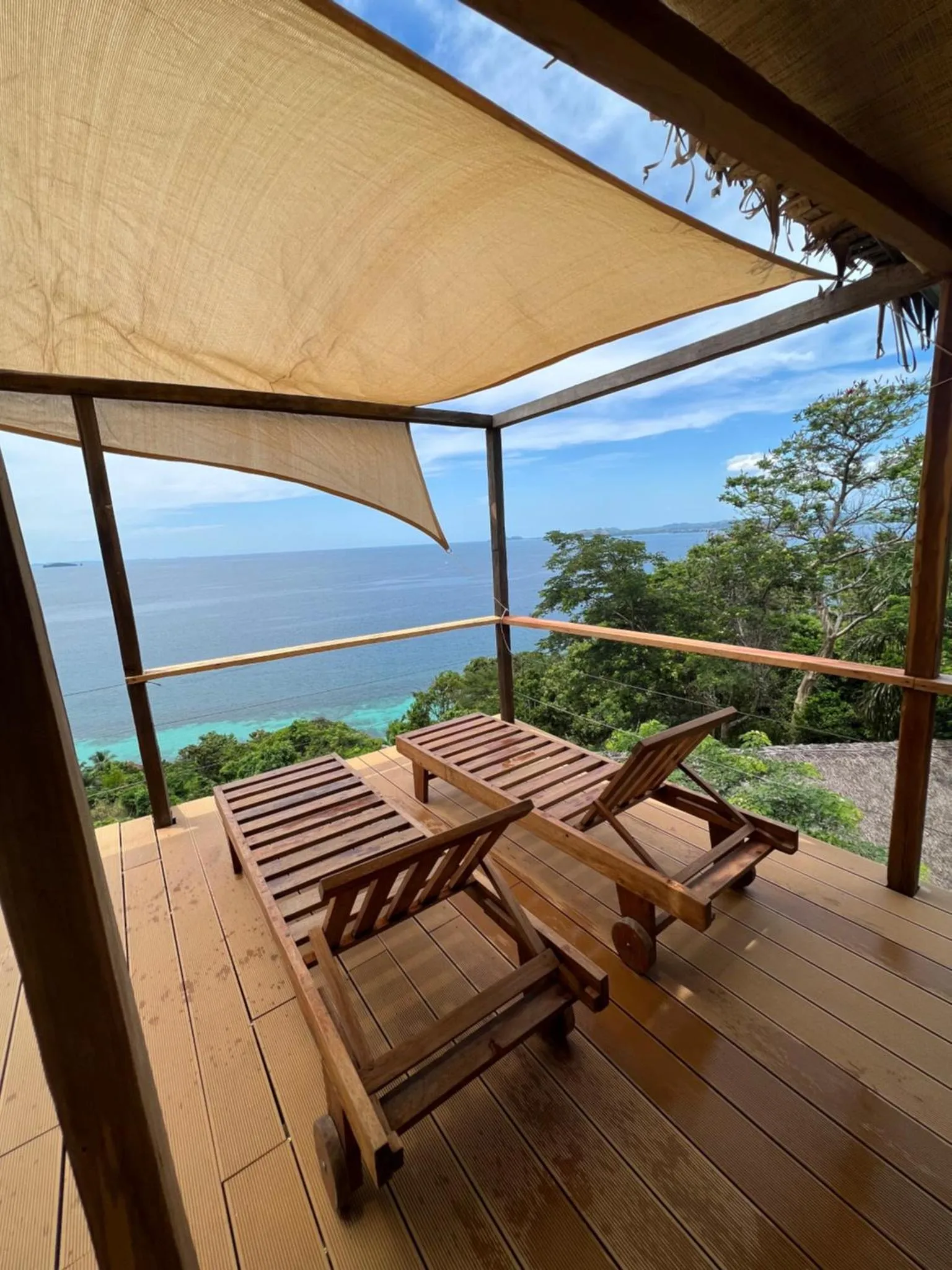 Deux transats en bois invitent à la détente sur une terrasse ensoleillée avec vue sur la mer.
