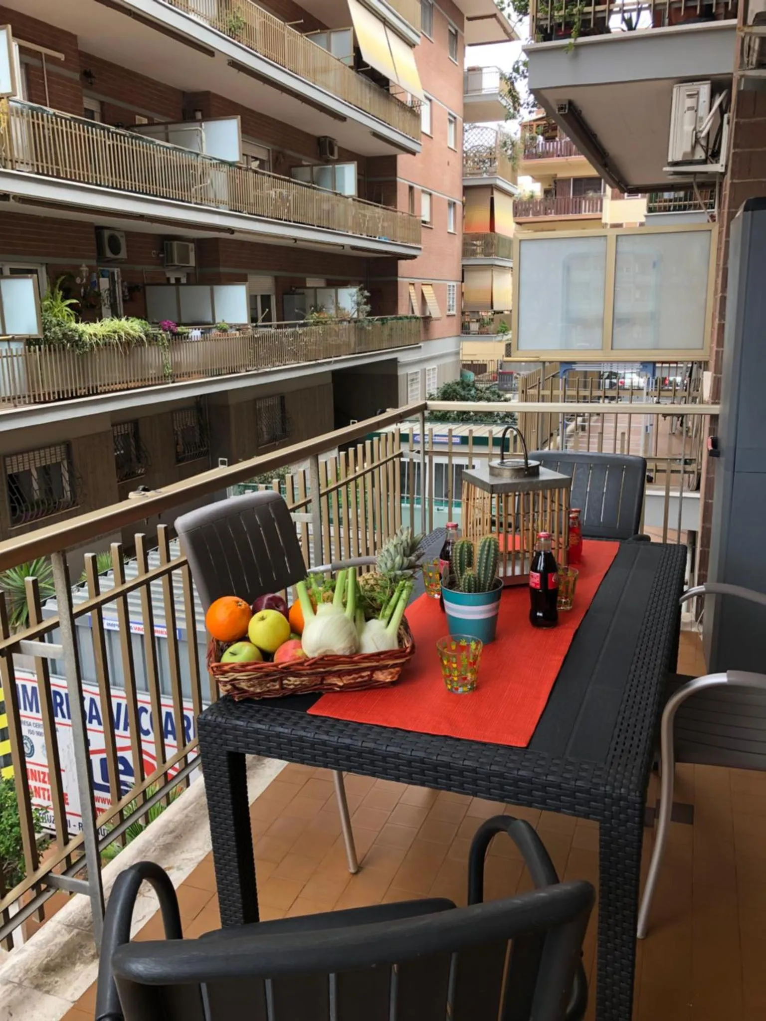 Une table avec des fruits et des boissons est mise en scène sur une terrasse ensoleillée.