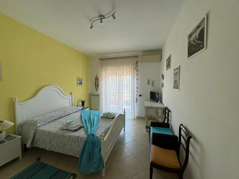 Une chambre lumineuse avec un grand lit et un accès à une terrasse.