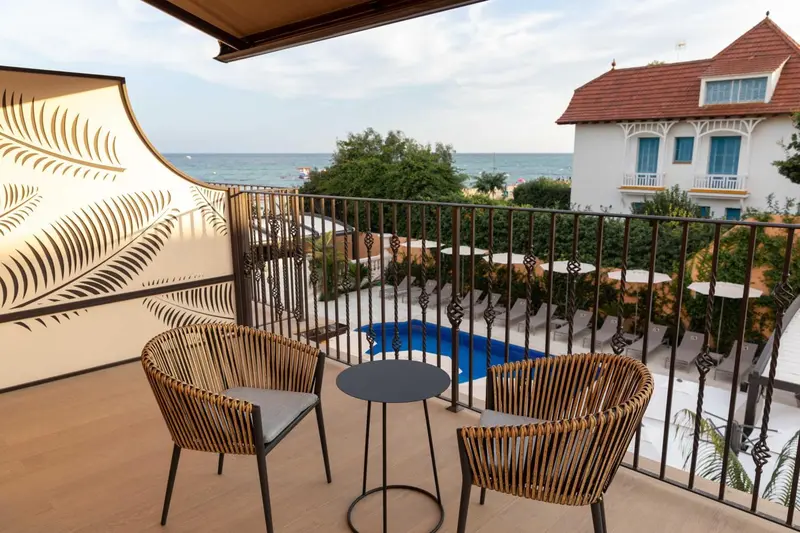 Terrasse aménagée avec mobilier en rotin donnant sur une piscine et la mer.