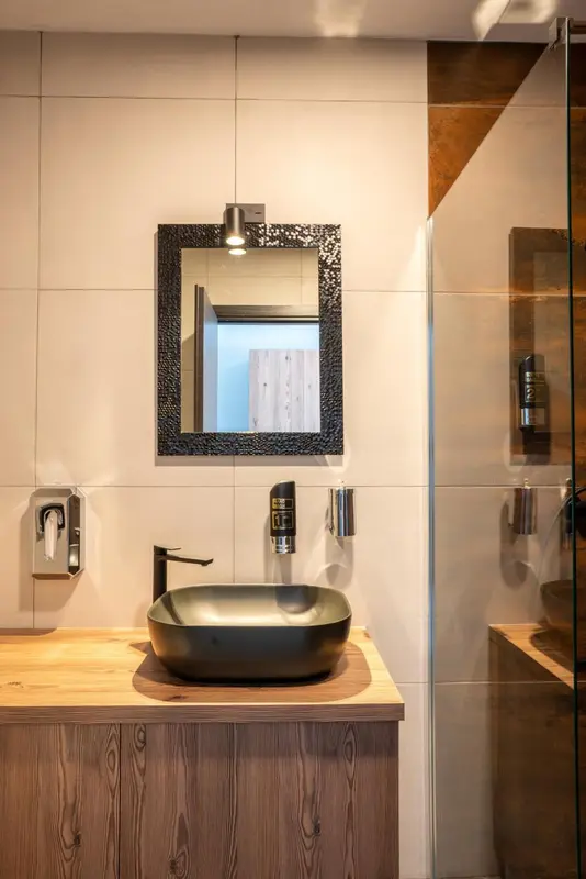 Un lavabo moderne sur un meuble en bois clair dans une salle de bain carree.