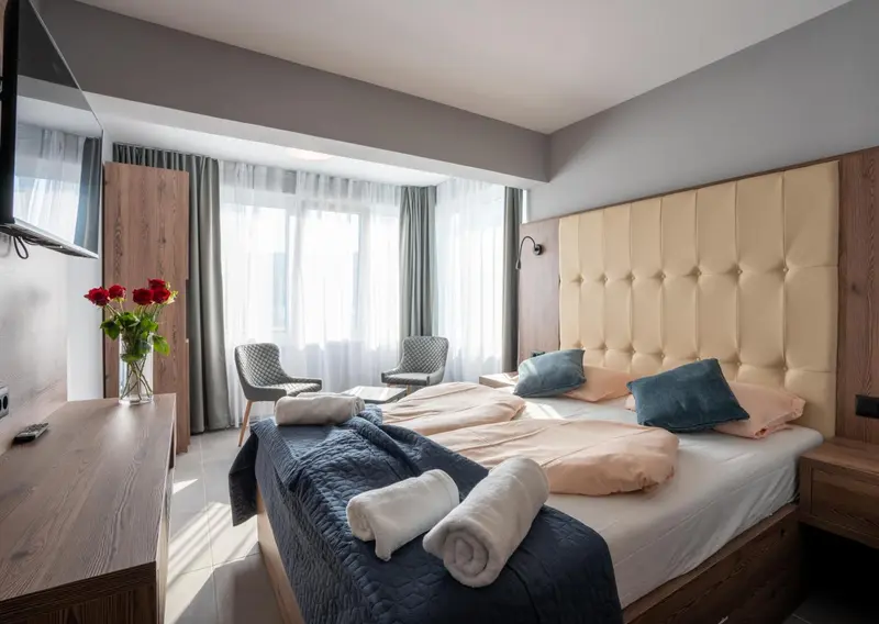 Une chambre d'hôtel lumineuse avec un grand lit et des fauteuils.