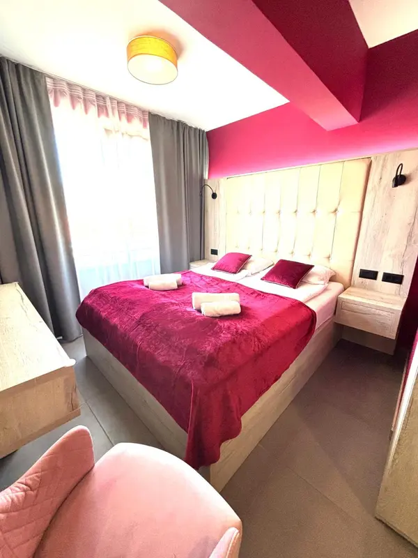 Une chambre à coucher avec un grand lit recouvert d'une courtepointe rouge et des oreillers.