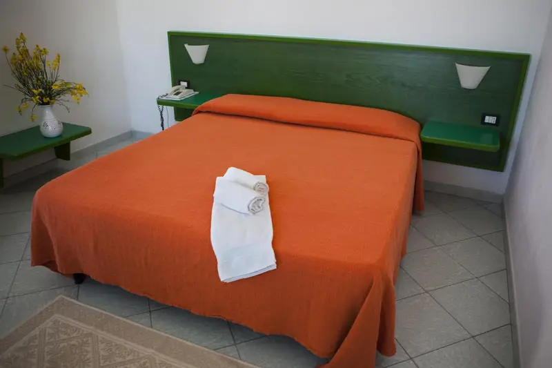 Une chambre avec un lit recouvert d'une couverture orange et d'oreillers blancs.