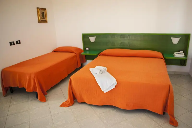 Deux lits simples avec couvertures orange dans une chambre lumineuse.