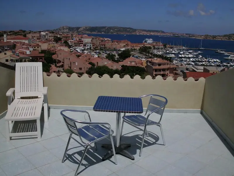 Terrasse avec mobilier d'extérieur donnant sur une ville côtière et un port de plaisance.