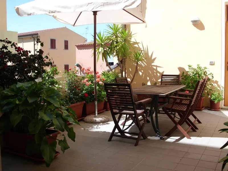 Une table et des chaises en bois sont disposées sur une terrasse fleurie.