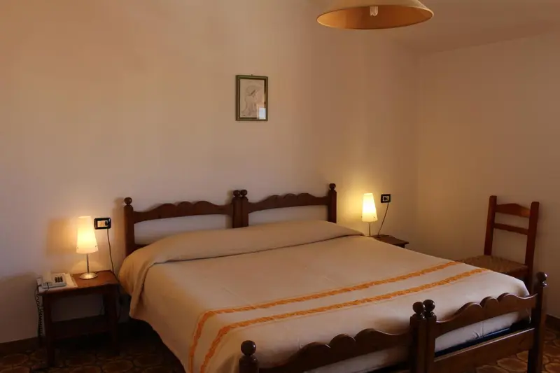 Une chambre lumineuse avec un grand lit recouvert d'une courtepointe.