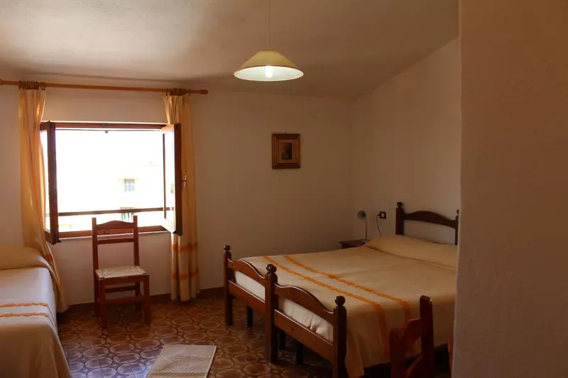 Une chambre lumineuse avec deux lits simples et une fenêtre.