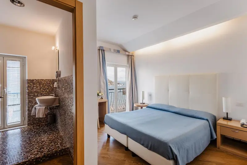 Une chambre lumineuse avec un lit double et une salle de bain ouverte.