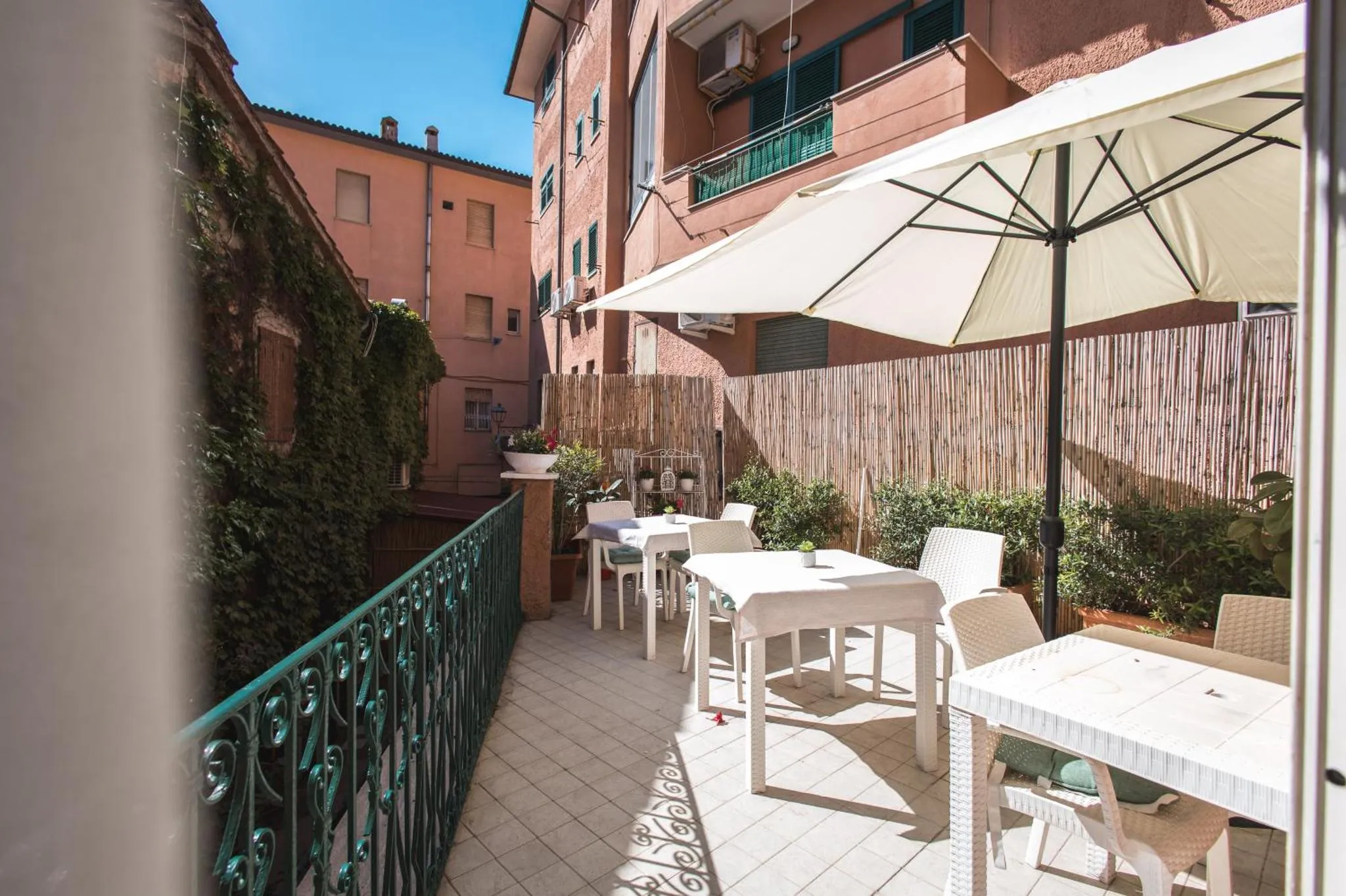Terrasse ombragée avec tables et chaises blanches.