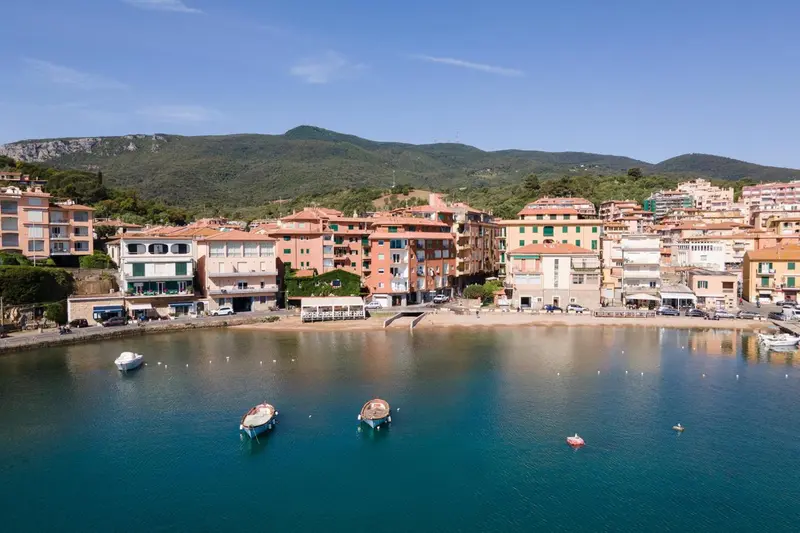 Vue aérienne d'une petite ville côtière avec des bâtiments aux toits rouges et une plage.