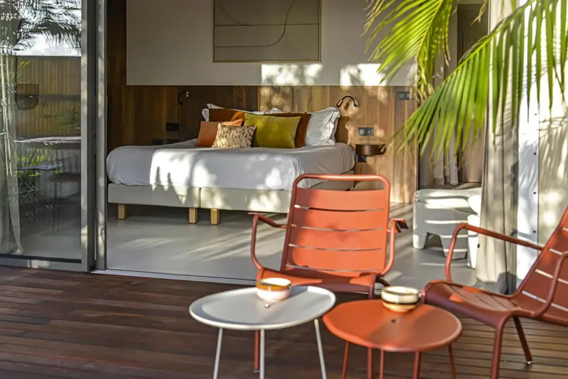 Une chambre lumineuse s'ouvre sur une terrasse en bois.
