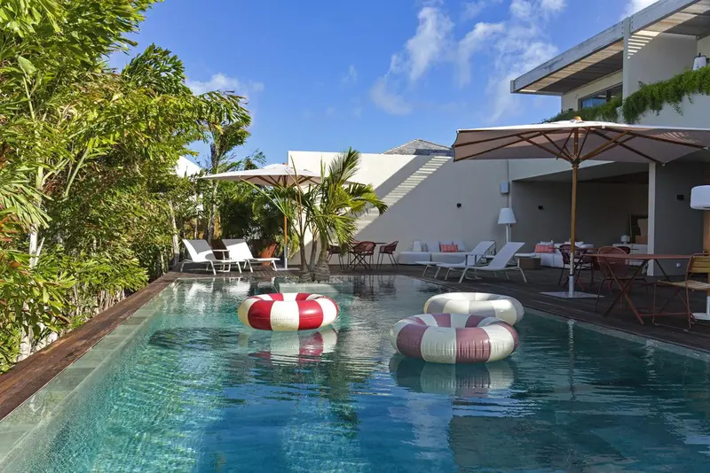 Une piscine rectangulaire bordée de chaises longues et de parasols rouges.