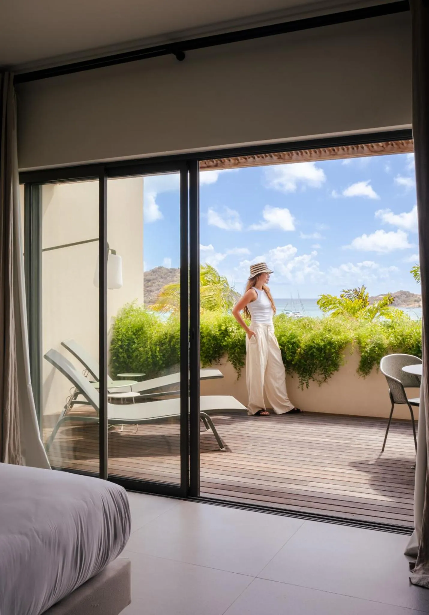 Une femme se tient sur une terrasse ensoleillée avec vue sur la mer.