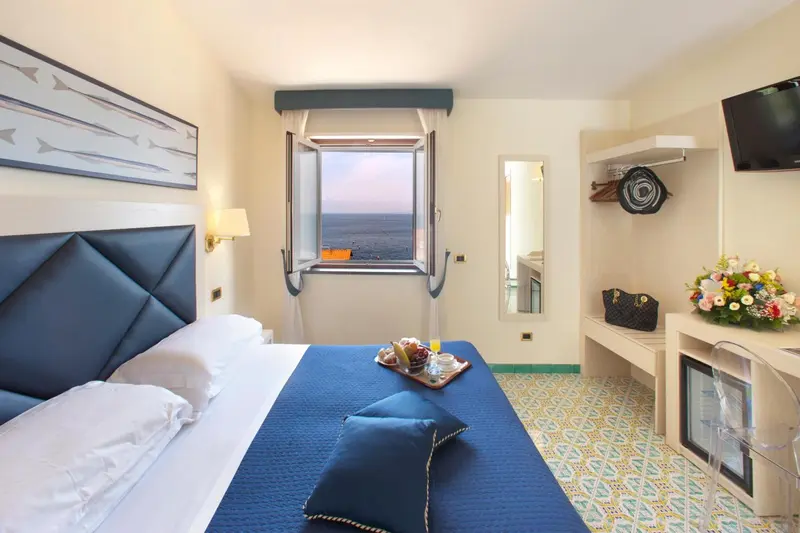Chambre lumineuse avec un lit double et vue sur la mer.
